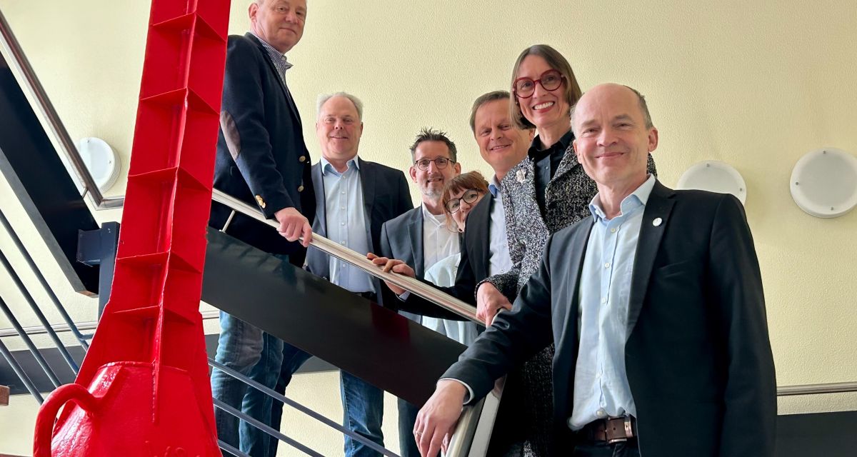 Auf einer Treppe neben einer roten Boje stehen Mitarbeitende des Wsserstraßen- und Schifffahrtsamtes Weser-JadeNordsee- Von links: Stpha Hellwig, Dirk Eickmeyer, Ulrich Günther, Julia Janssen, Rüdiger oltmanns, Eva Sieder, Torsten Stengel