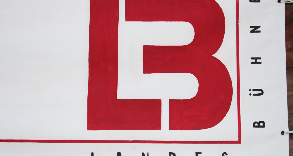 Auf dem Foto ist das Logo der Landesbühne, ein rotes stilisiertes 