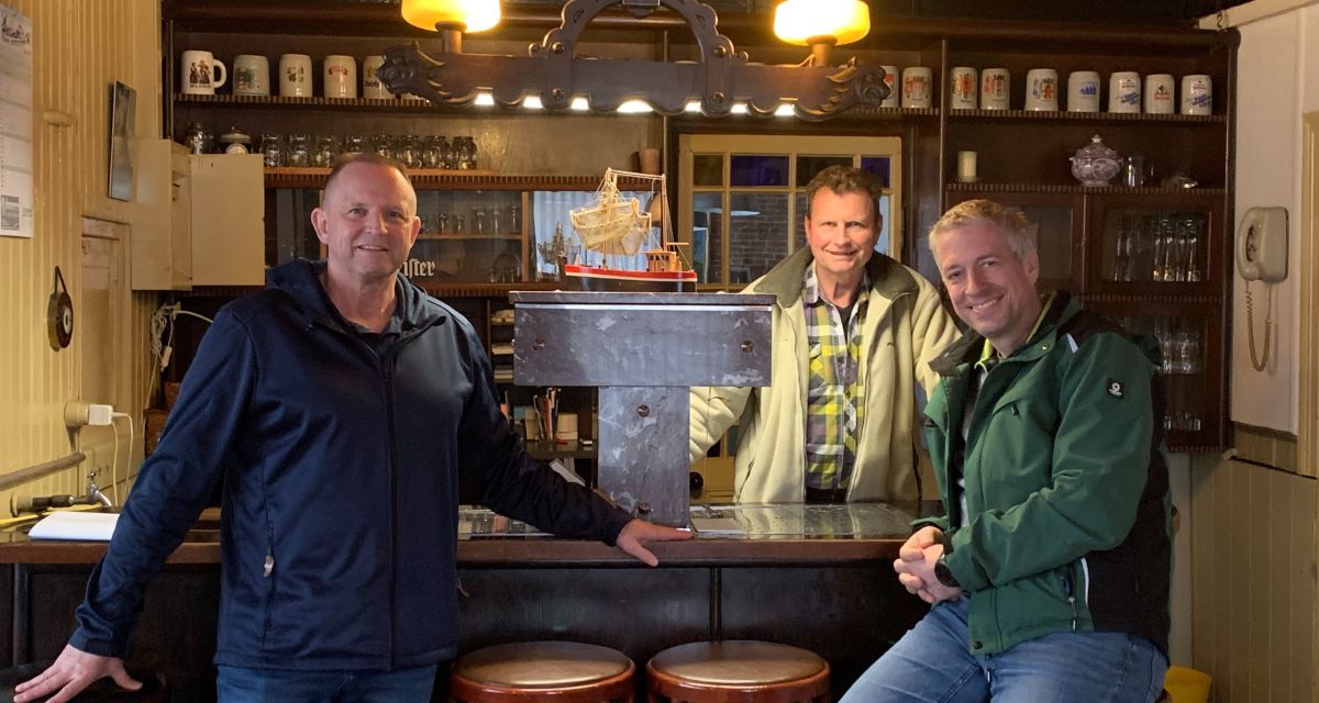 Zu sehen ist der Vorstand des Vereins zur Erhaltung historischer Gebäude Sillenstede. Von links: René Fabian (Beisitzer), Jan Bölts (Vorsitzender der Dorfgemeinschaft, Hauseigentümer des Ohmstede-Gebäudes) und Hinrich Neumann (Vorsitzender des Vereins zur Erhaltung historischer Gebäude Sillenstede). Sie stehen an der Theke der historischen Kneipe im Ohmstede-Gebäude. 