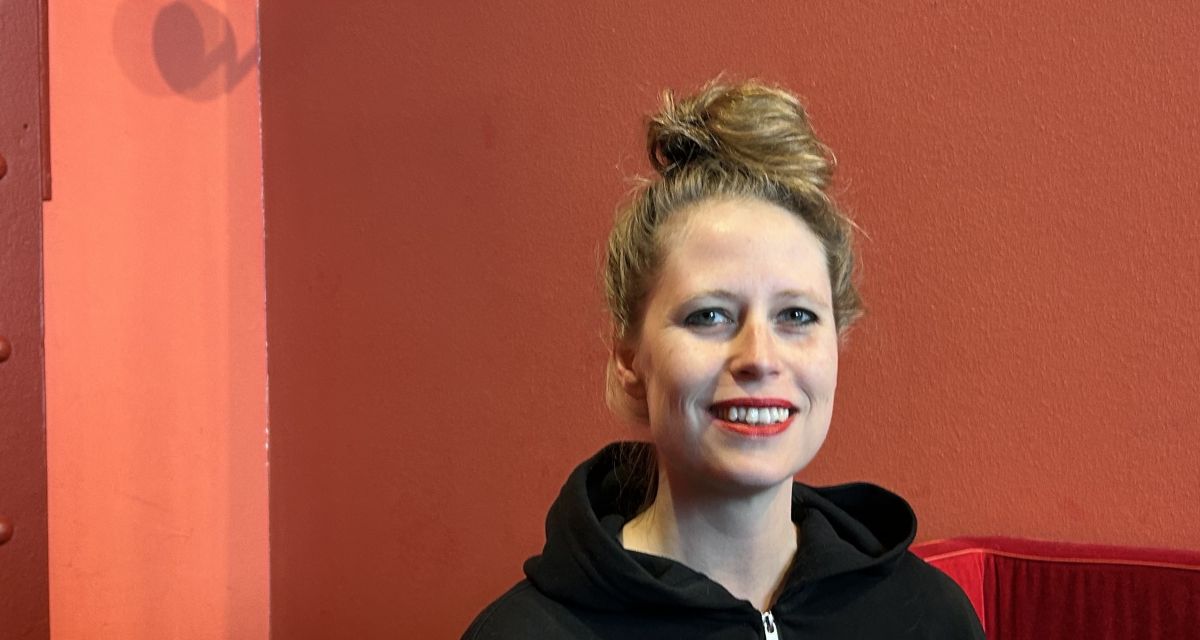 Zu sehen ist die Bünenautorin Vera Schindler vor einer roten Wand