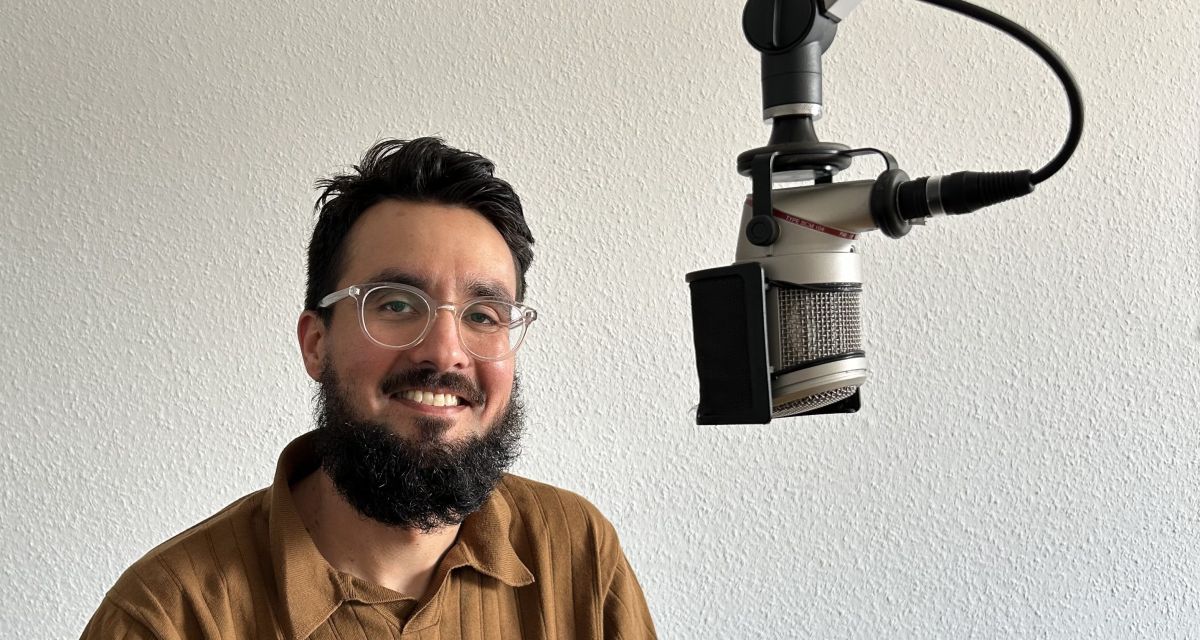 Zu sehen ist ein eher junger bärtiger Mann mit Brille im radiostudio. Es handelt sich um Julien Rathje, Kurator der Wilhelmshavener Kunsthalle.