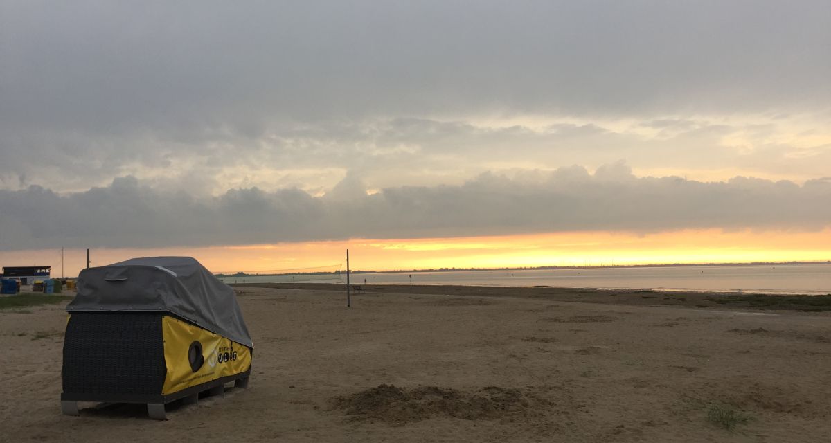 Man sieht einen Schlafstrandkorb am Dangaster Strand bei Sonnenuntergang.