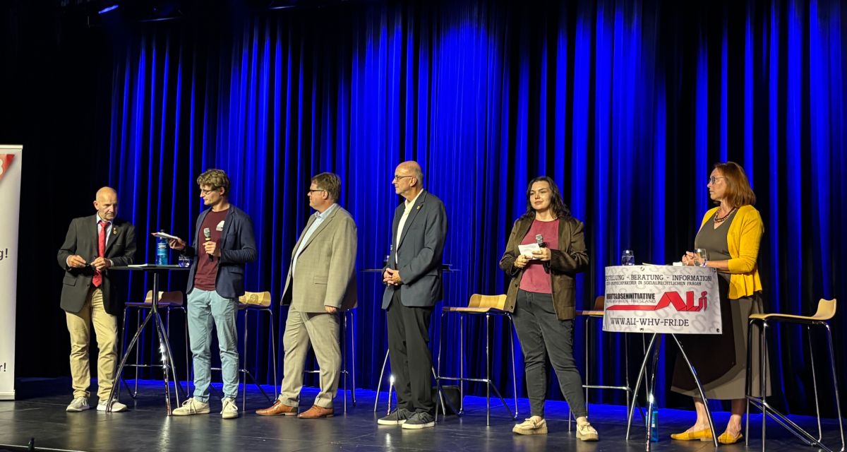 Auf de Bühne des Pumpwerks diskutieren v.l.n.r.. Andreas Tönjes (Die Partei); Marco Bünger (DGB), Volker Block (SPD), Frank Uwe Walpurgis (UWG) Bente Hoeft -Heyn (Radio Jade) und Dr. Eva-Maria Haarmann (parteilos)
