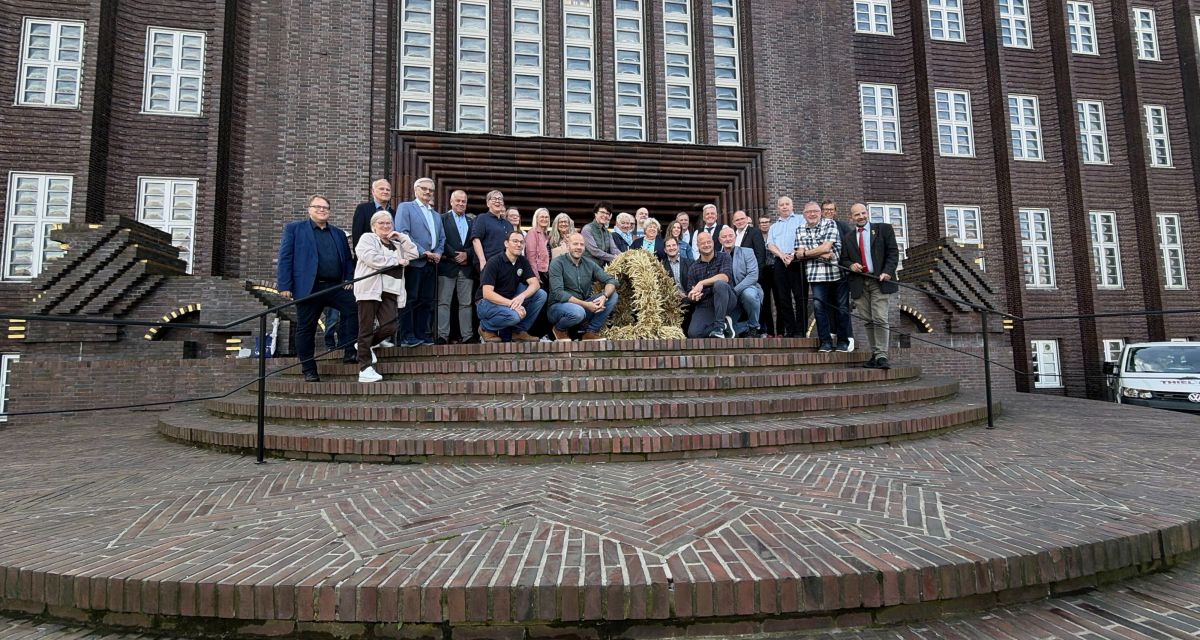 Vertreter*innen von Landwirtschaft und Politik und Verwaltung in Wilhelmshaven posieren mit der Erntekrone vor dem Rathaus in Wilhelmshaven 