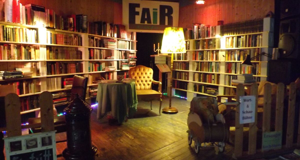 Bühne des fair Cafe. In der Mitte stehen ein Sessel und eine Stehlampe.