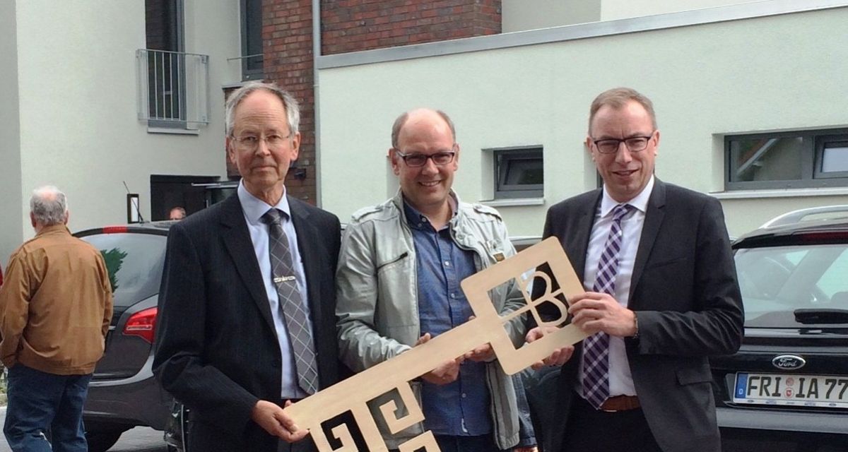 Drei Männer halten einen grossen goldenen Schlüssel in die Kamera