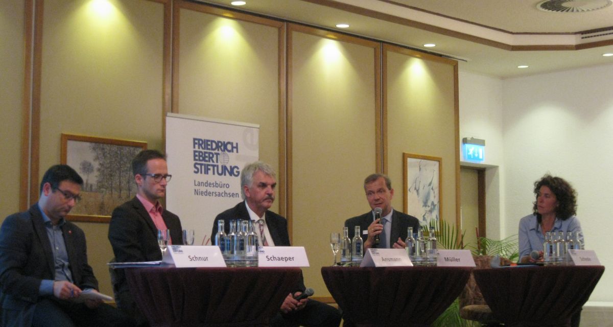Vier Männer und eine Frau diskutieren bei einer Podiumsdiskussion.