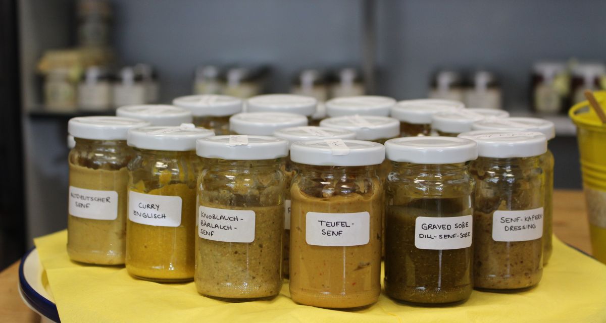 mehrere Senfgläser stehen auf einer gelben Tischdecke