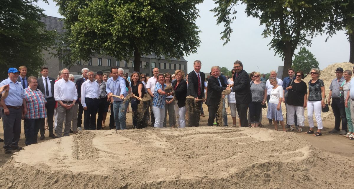 Auf dem Foto sieht man die Unterstützer des neuen Hospizes, die mit einem Spaten Sand in die Luft werfen
