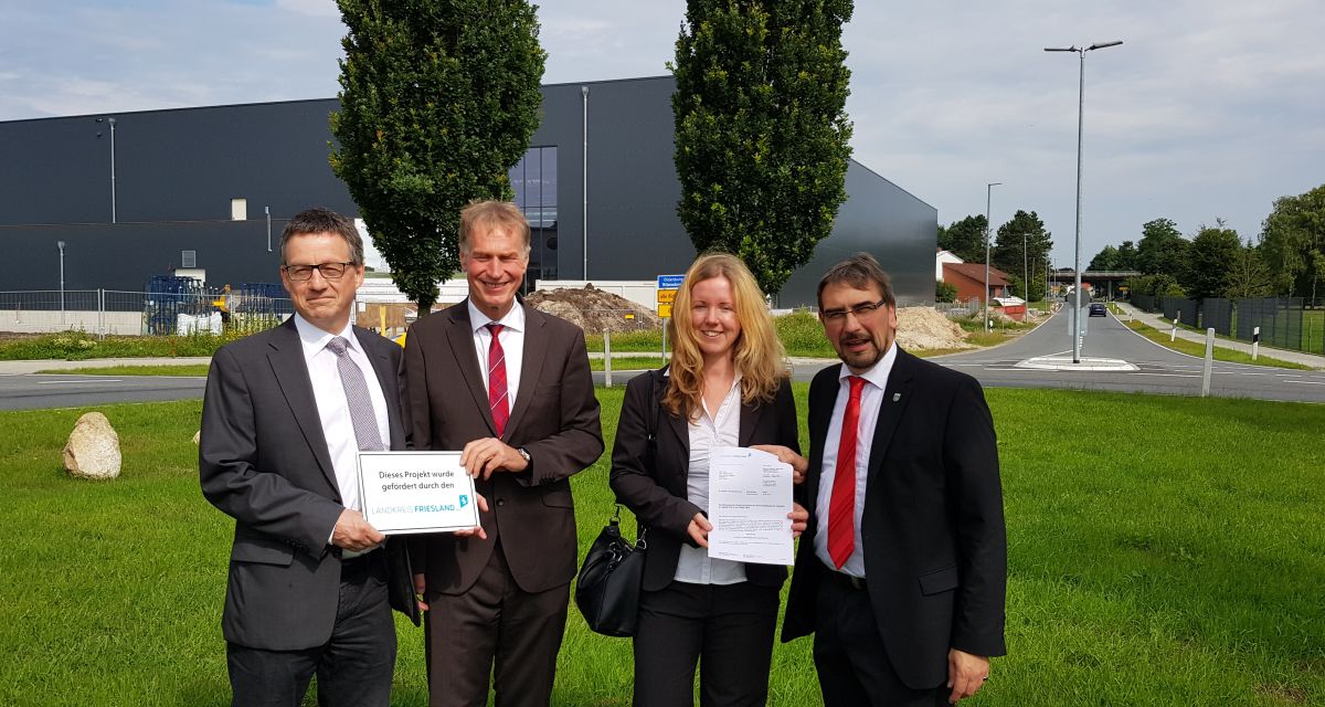 Drei Männer und eine Frau posieren mit einem Dokument für die Kamera.