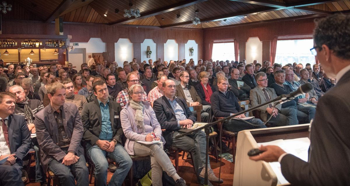 Mehrere Menschen lauschen sitzend einem Redner.