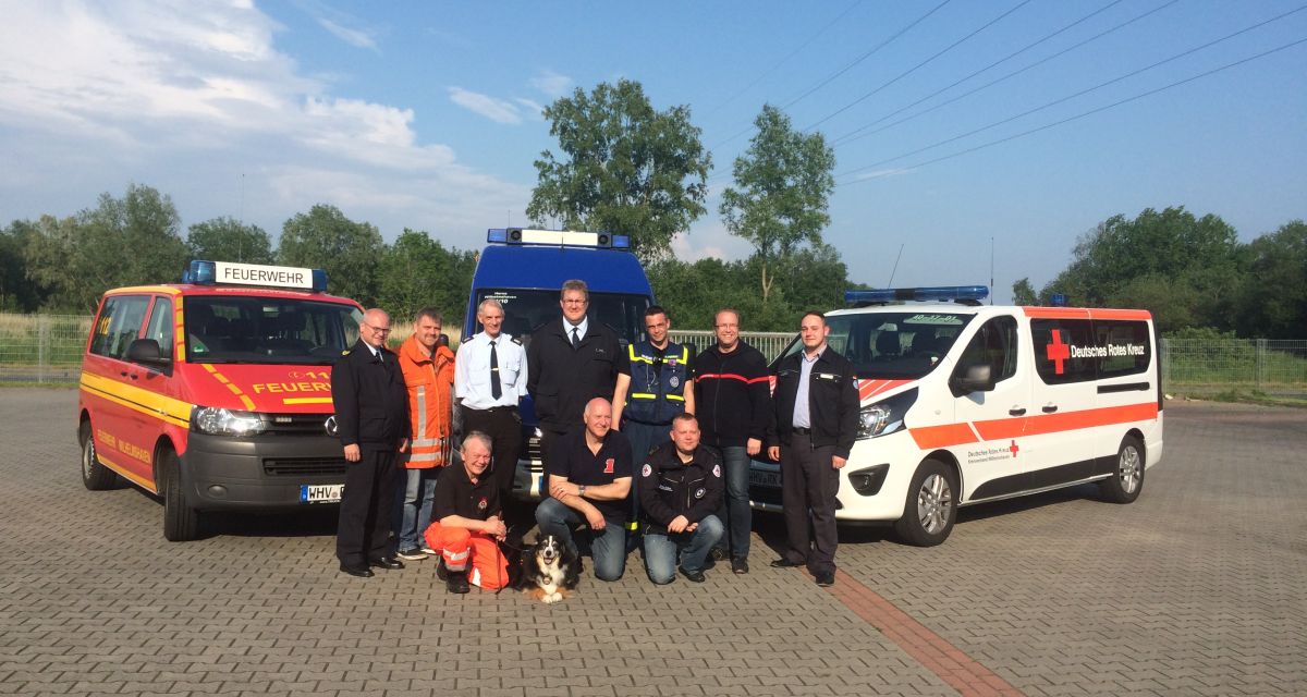 Polizisten, Feuerwehrmänner und Sanitäter vor ihren Einsatzwägen.
