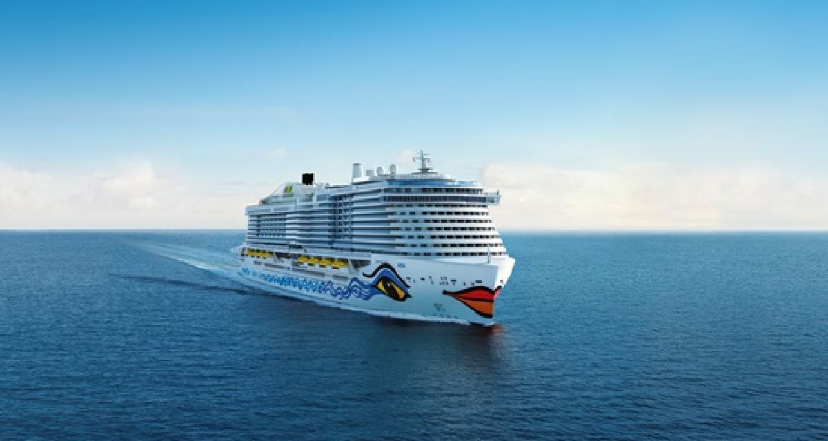 Zu sehen ist ein Schiff der AIDA Flotte mit der typischen Bemalung: große Augen auf den Seiten und ein roter Mund am Bug. Das Schiff ist auf dem Meer unterwegs.