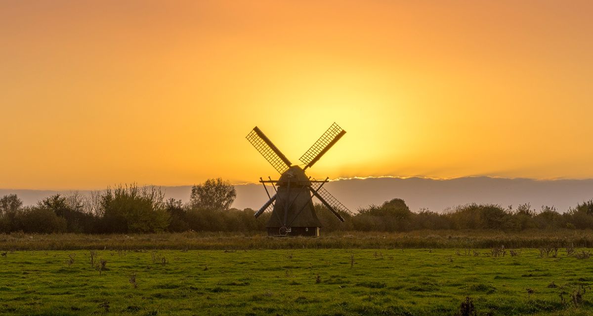 Die Wasserschopfmühle bei Neustadtgödens vor einem orangenen Himmel. 