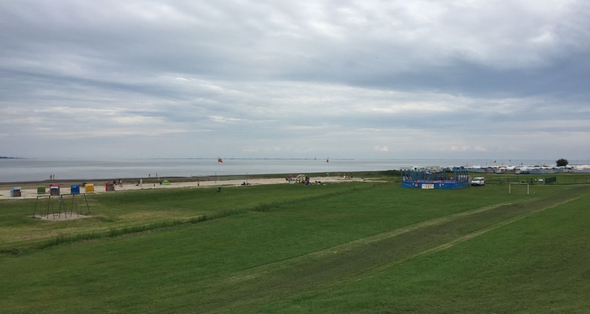 Man sieht den Strand in Dangast neben dem Campingplatz, in der Ferne den Schlafstrandkorb