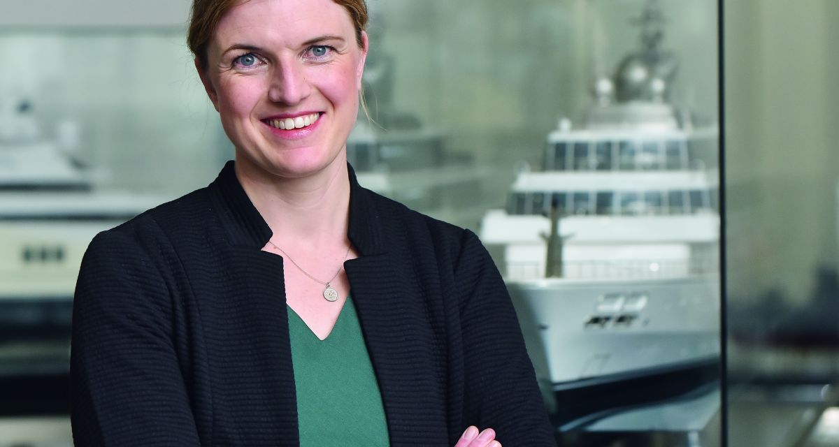 Lena Stroebele, Geschäftsführerin der Lürssen Werft steht vor einem Modell eines Schiffs. 