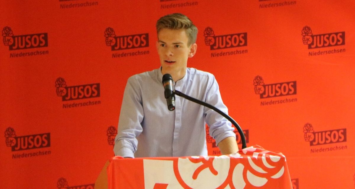 Jannes Wiesner von der SPD steht vor einem Jusos-Plakat hinter einem Rednerpult