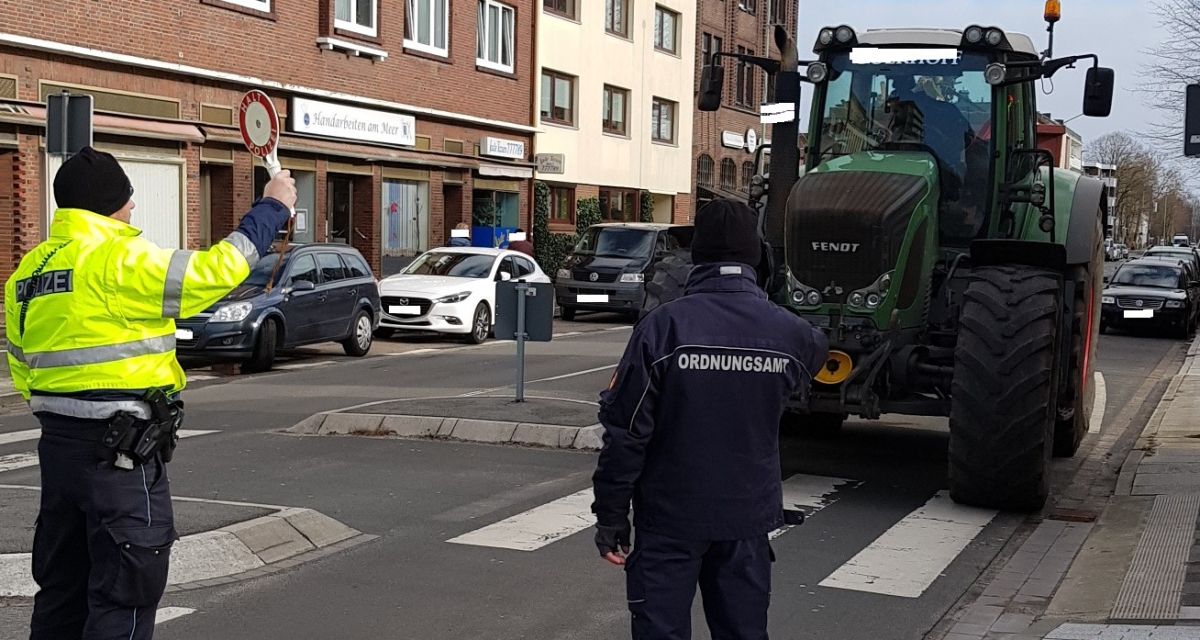 Ein Traktor wird von einem Polizisten und einem Mitarbeiter des Ordnungsamtes angehalten.