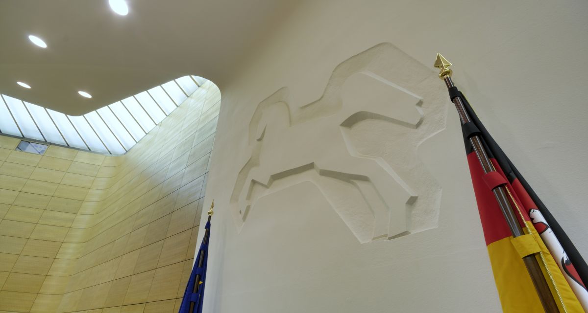 Säule an der Stirnseite des Plenarsaals mit dem Niedersachsenross in Form eines Reliefs von Professor Kurt Schwerdtfeger eingerahmt von der Europa- und der Niedersachsenflagge 