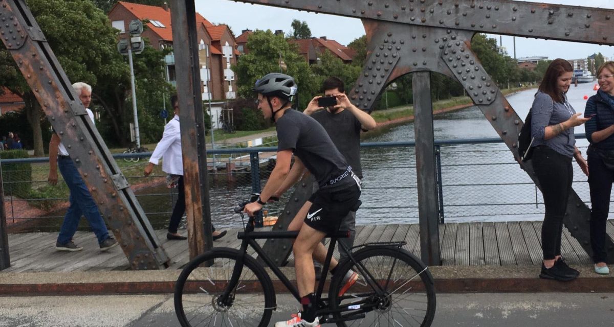Ein Triathlet fährt beim Nordseeman mit dem Fahrrad über die Deichbrücke. 