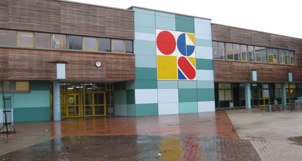 Das Bild zeigt den Eingangsbereich der IGS Wilhelmshaven von außen bei Regen.