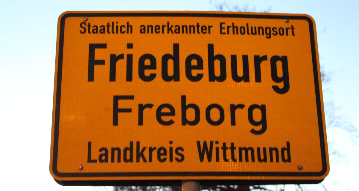 Zu sehen ist ein gelbes Ortseingangsschild der Stadt Friedeburg. Friedeburg trägt den Titel
