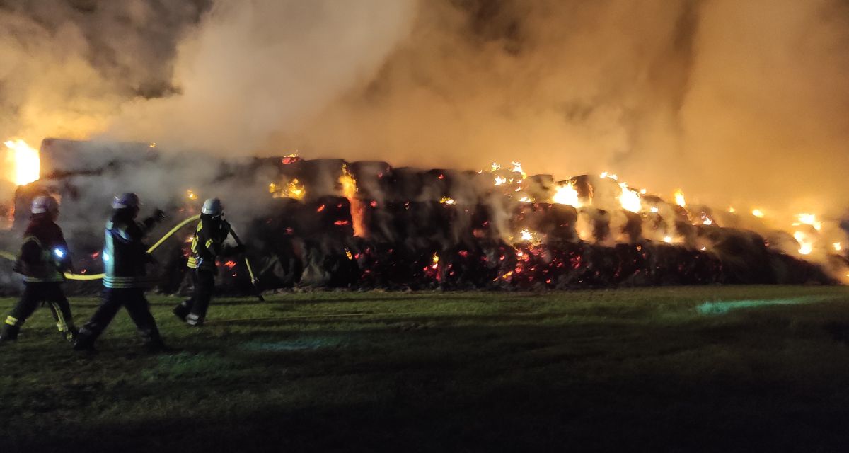 Feuerwehrmänner bekämpfen nachts brennende Strohballen