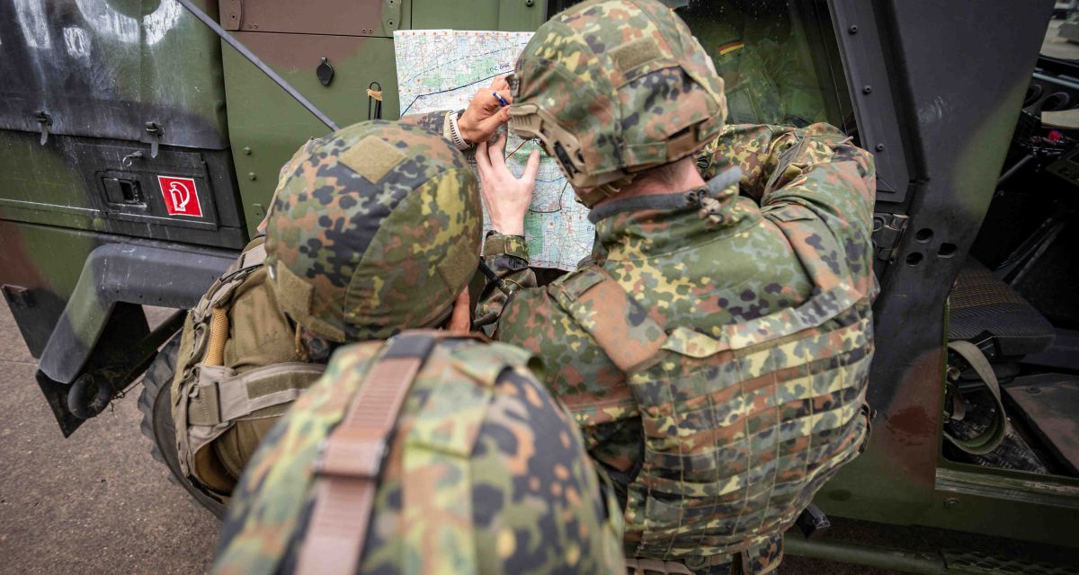Drei Soldat:innen studieren eine Landkarte während der Übung 