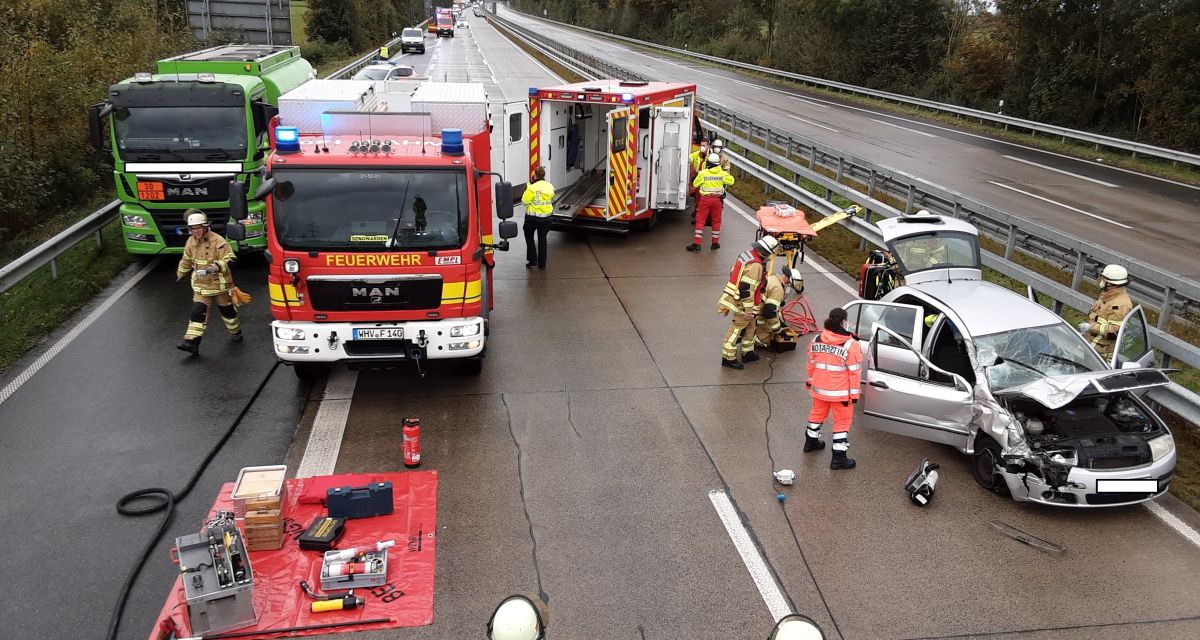 Auf dem Bild ist die Unfallstelle auf der A29 zu sehen. Die Einsatzwagen der Feuerwehr stehen mitten auf der Fahrbahn. Auch der Unfallwagen und der Tanklaster sind zu sehen. 
