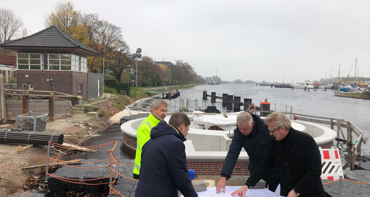 Verantwortliche der Erneuerung des Dükers an der Deichbrücke in Wilhelmshaven zeigen auf eine Zeichnung