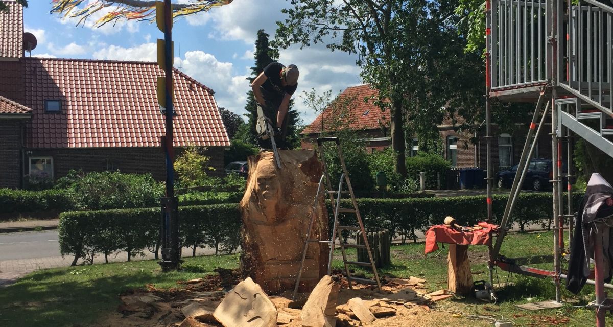 Bildhauer mit Kettensäge auf einem Baumstamm