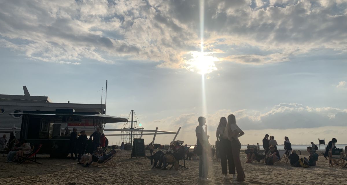 Nachmittagssonne am Strand von Dangast. Junge Menschen stehen vor dem Wasser beim Jugendpolitischen Barcamp in Dangast