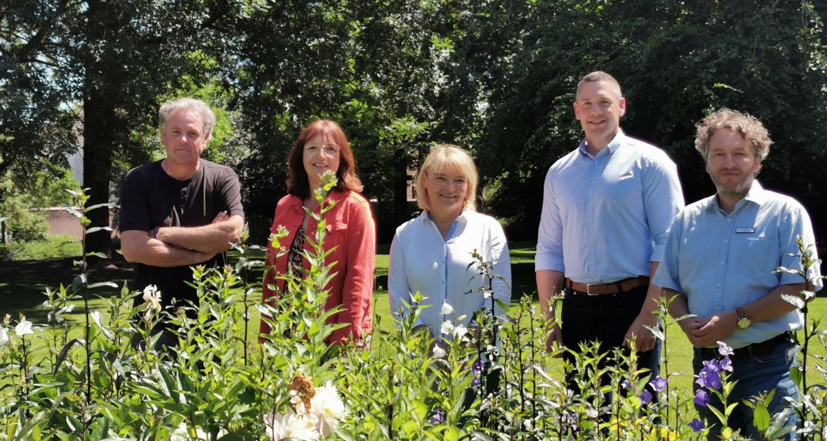 Verteter*innen des Jobcenter Friesland und des Schlossmuseums Jever stehen bei Sonnenschein im Schlossgarten Jever