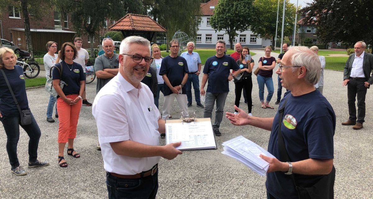 Die Unterschriften zum Bürgerentscheid für das Dorfgemeinschaftshaus Cäciliengroden werden an Sandes Bürgermeister Stephan Eiklenborg übergeben.