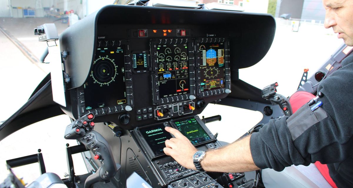 Man sieht das Armaturenbrett eines Hubschraubers, das ein Pilot bedient.