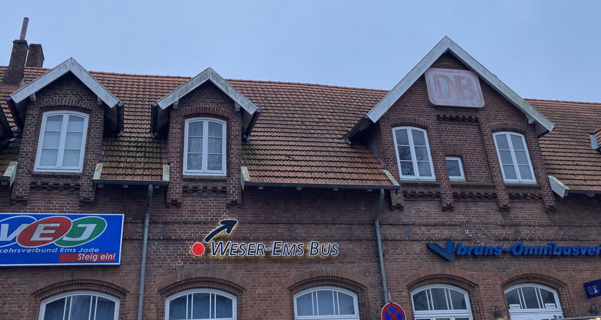 Die verschiedenen Verkehrsgesellschaften am Bahnhof in Jever sind über Leuchtreklamen am Bahnhofsgebäude angebracht.