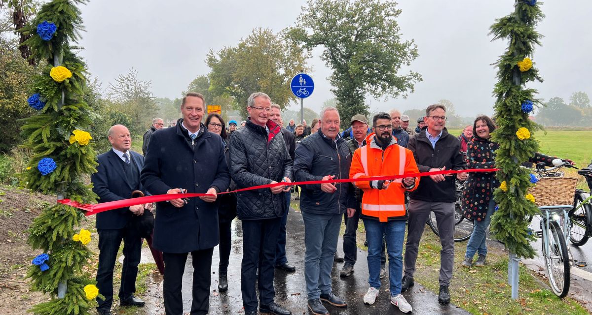 Vertreter schneiden ein Band zur Einweihung eines Radweges durch.