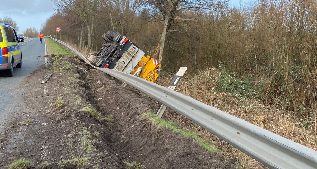 Zu sehen ist ein umgestürztes Baustellenfahrzeug auf der Berme der Bundesstraße B210. Die Leitplanke wurde beim Abkommen des Fahrzeugs von der Fahrbahn beschädigt.