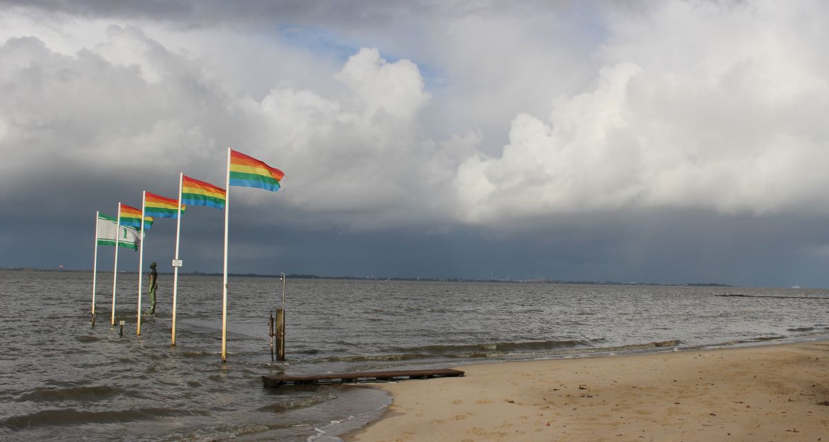Hochwasser in Dangast, im Wind wehen Regenbogenflaggen