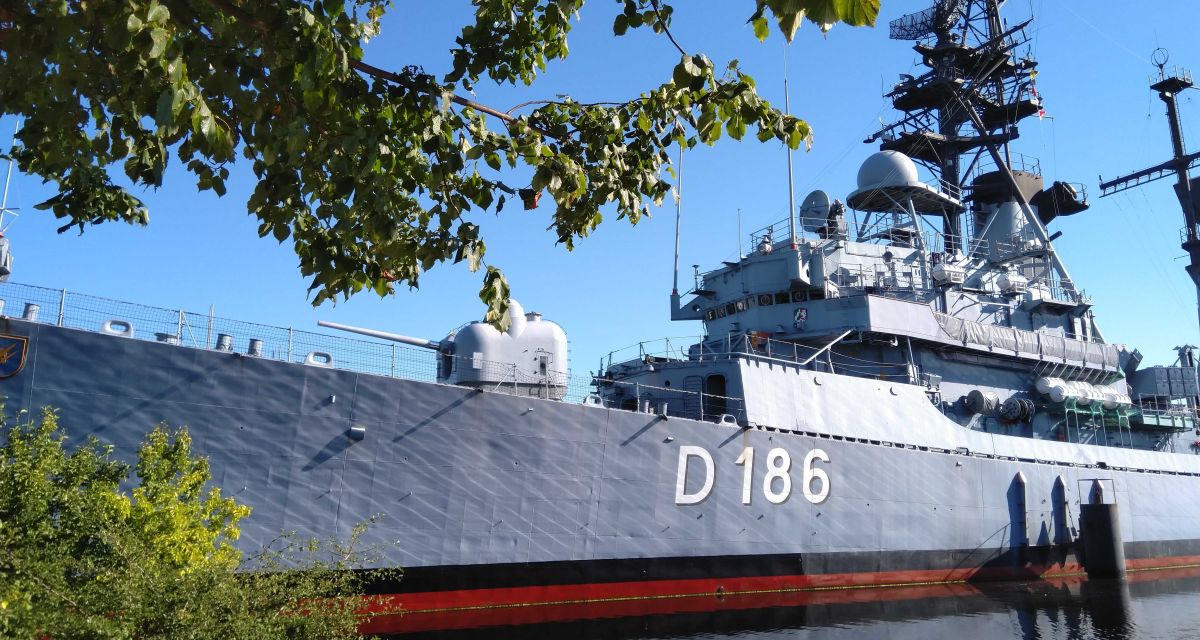 Zu sehen ist der Lenkwaffenzerstörer Mölders, wie er im Wasser bei Wilhelmshaven liegt.