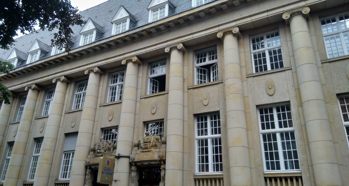 Zu sehen ist die Hauptzentrale der Oldenburgischen Landesbank in Oldenburg. Das Gebäude ist neoklassizistisch gehalten, mit Säulen aus Sandstein und hohen Fenstern.