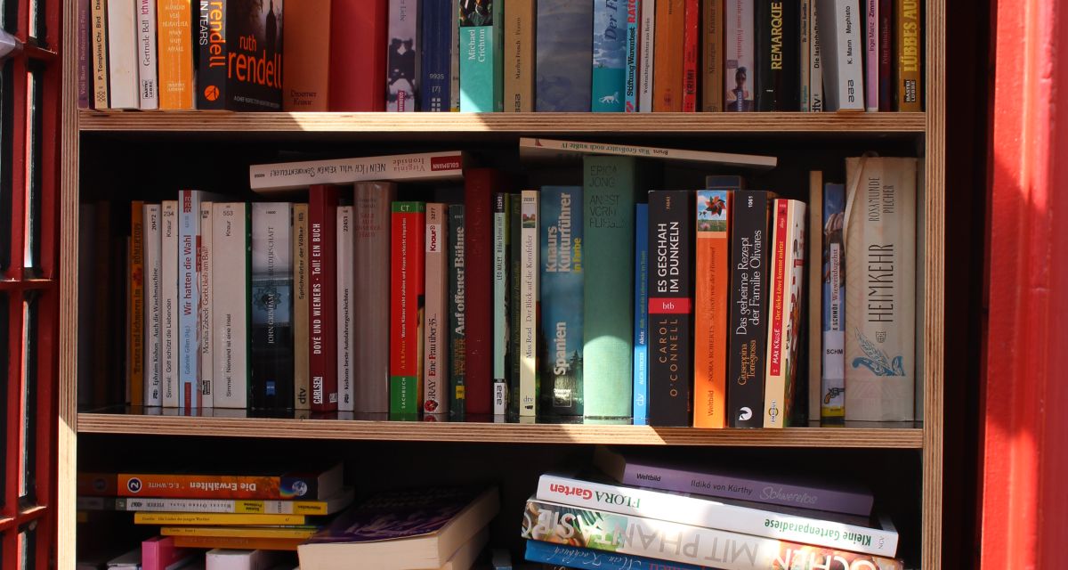 Das Bild zeigt eine rote Telefonzelle, die als öffentlicher Bücherschrank umfunktioniert wurde, eine 