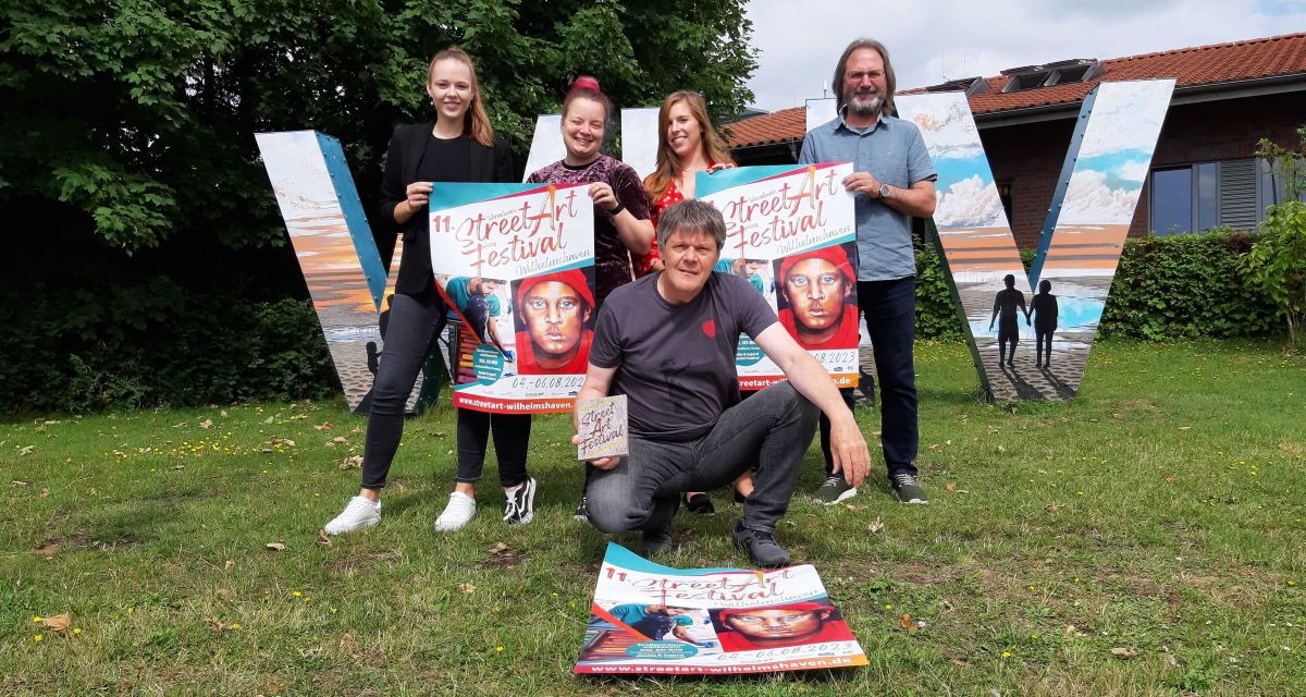 Vertreter*innen der Wilhelmshaven Touristik & Freizeit stellen das 11. StreetArt Festival Wilhelmshaven vor. Vor großen Buchstaben 