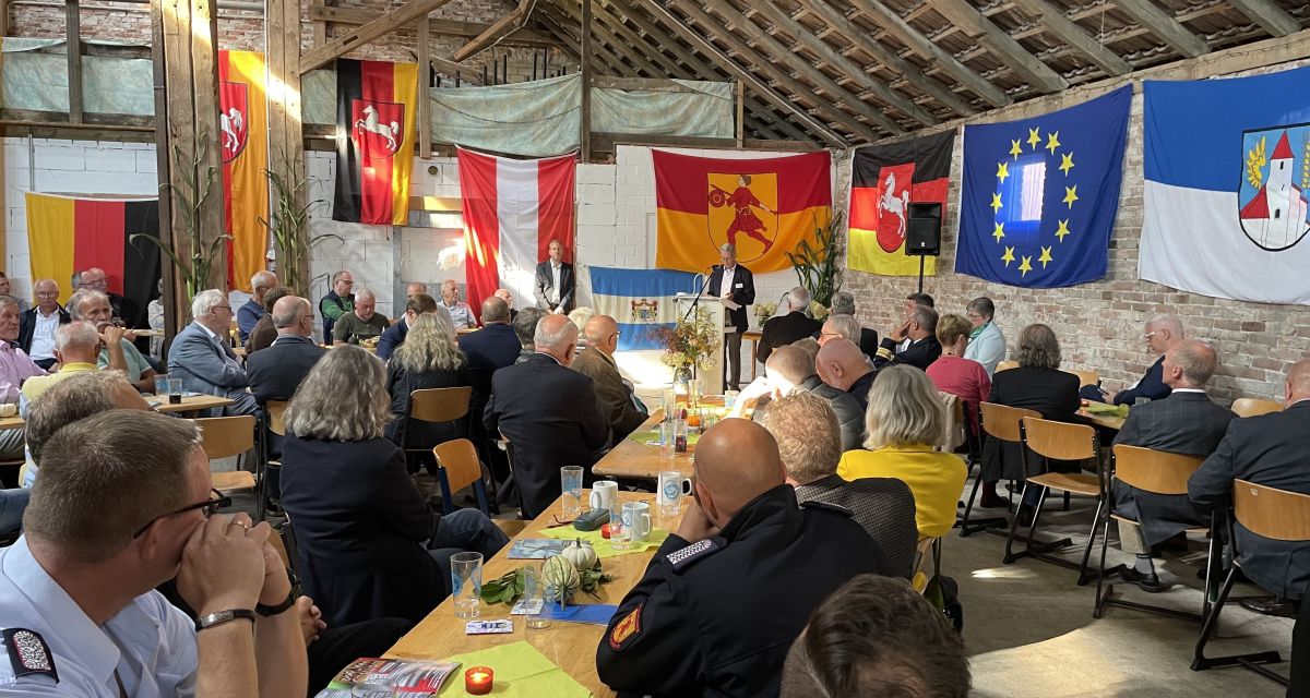 Politischer Frühschoppen zum 405. Sengwarder Markt. Die Teilnehmer*innen sitzen an Tischen und hören Rednern zu. An den Wänden des Raums sind Europa-, Deutschland-, Niedersachsenflaggen sowie die Flagge der Stadt Wilhelmshaven aufgehängt.