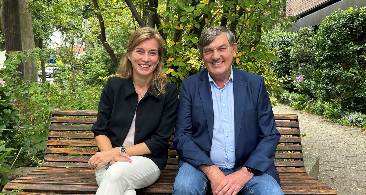 Siemtje Möller und Gerhard Böhling sitzen auf einer Bank vor einem Baum