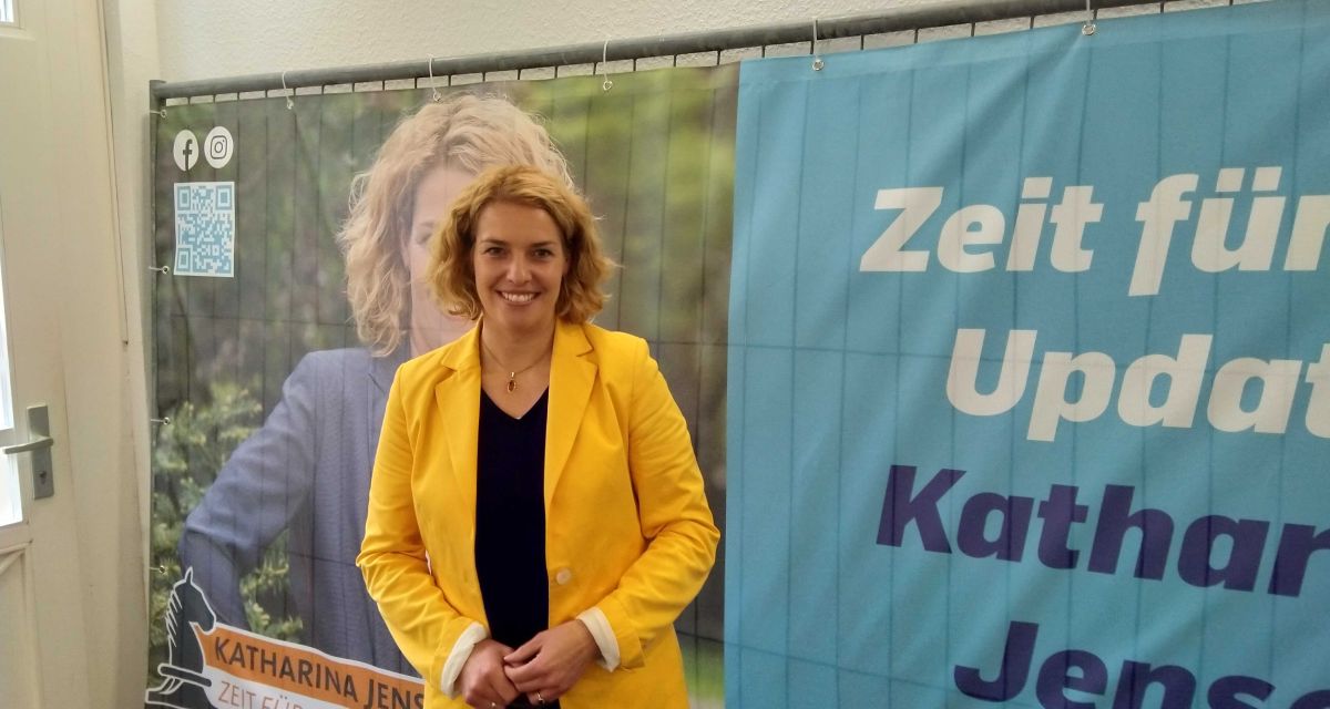 Katharina Jensen von der CDU steht vor einem Zaun mit ihrem Wahlplakat