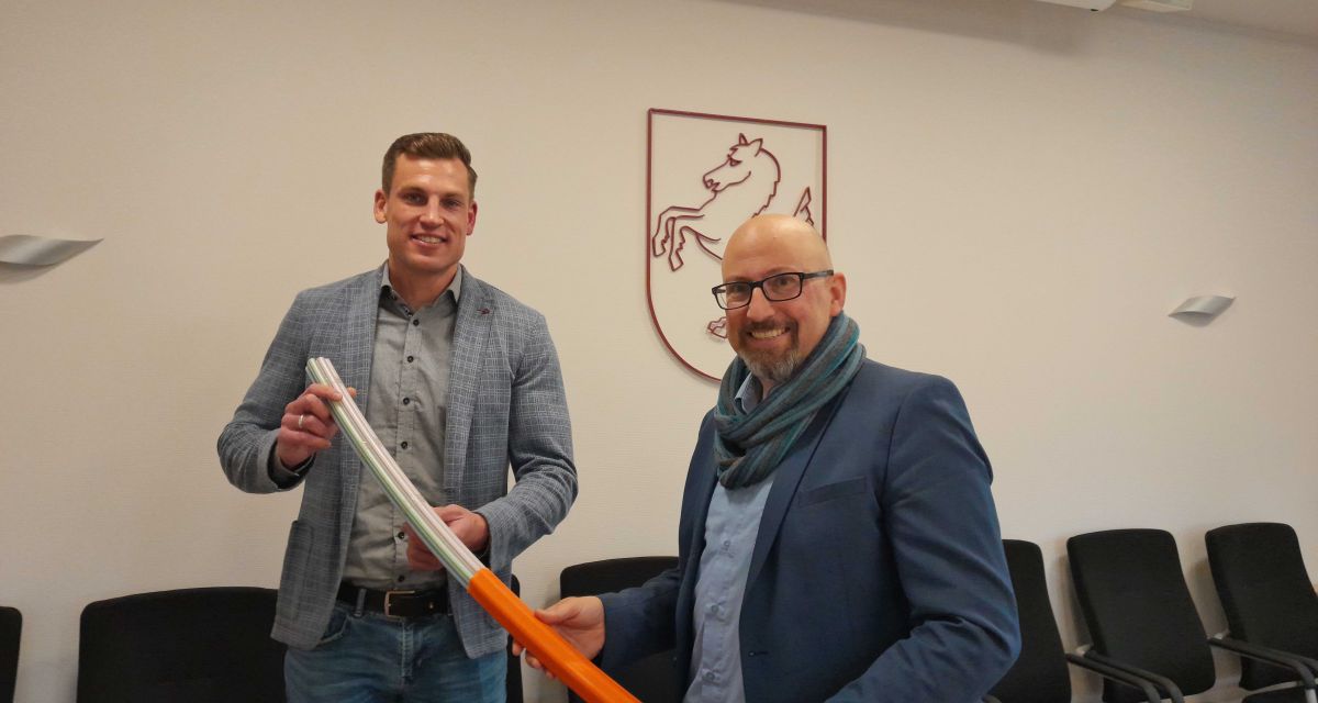 Zwei Vertreter der Stadt Schortens und der Deutschen Glasfaser präsentieren im Rathaus in Schortens ein Stück Glasfaserleitung, wie es künftig auch nach Accum, Grafschaft und Sillenstede verlegt werden soll.
