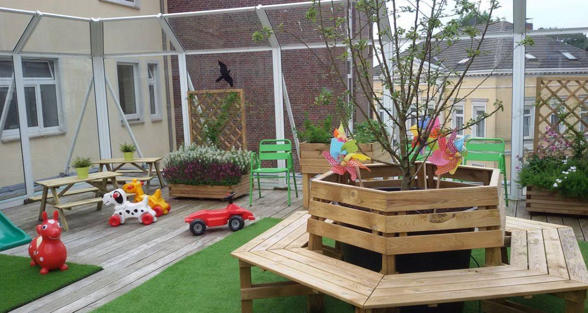 Auf der Dachterrasse befindet sich Spielzeug, sowie eine Sitzbank, die kreisförmig um einen Baum in der Mitte verläuft
