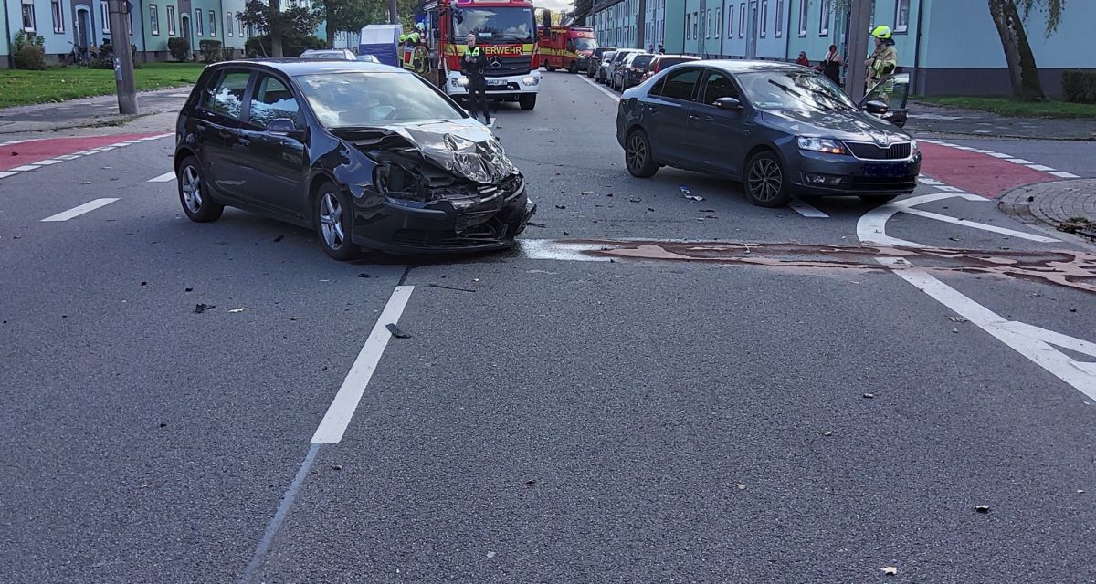 An der Kreuzung Preußenstraße/Dirschauer Straße in Fedderwardergroden stoßen am 13. Oktober 2024 zwei Pkw zusammen. Beide Fahrzeugführer können ihre Fahrzeuge selbstständig verlassen. Zu sehen sind die Wracks der beiden Autos auf der Kreuzung. Einsatzkräfte der Feuerwehr Wilhelmshaven und der Polizeiinspektion Wilhelmshaven/Friesland stehen zwischen den Autos, im Hintergrund ist ein Einsatzfahrzeug der Feuerwehr zu sehen.