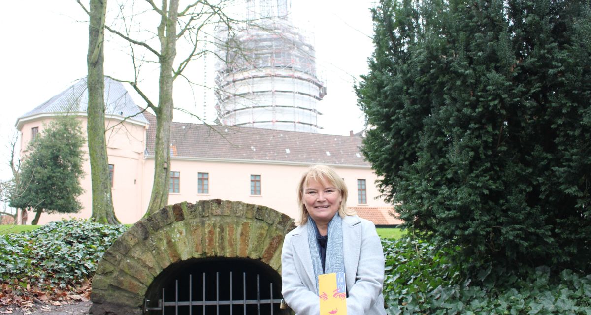 Dr. Antje Sander vom Schlossmuseum Jever stellt das Programm für das Jahr 2025 und die Pläne des Museums vor. Dabei steht sie vor dem unterirdischen Mariengang beim Jeverschen Schloss. Im Hintergrund ist der Schlussturm zu sehen. 